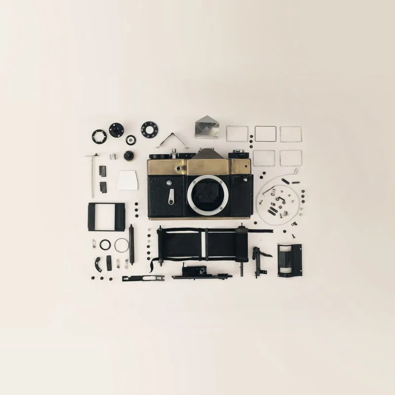 A camera and every one of its parts laid out and photographed on a chalk sweep