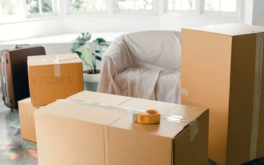 Labelled cartons and a sheeted armchair in a half-packed room