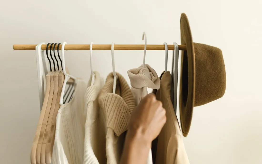 A rail of sample garments with a hand reaching along it